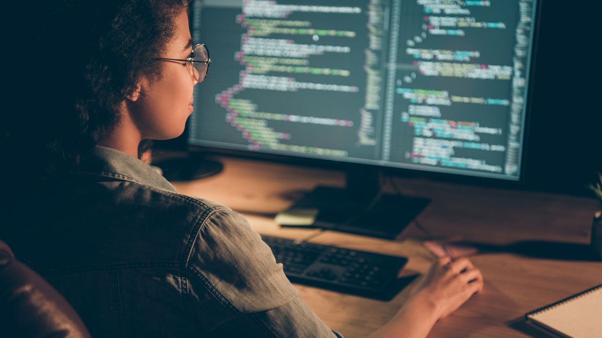 A female programmer working in front of a big monitor displaying code