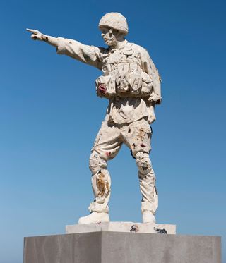 A statue of a soldier with full gear on pointing.