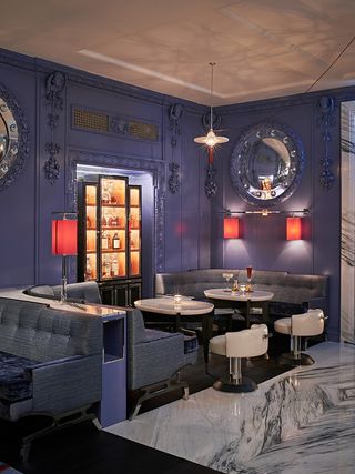 A seating area with the classic blue walls, silver furniture and red lampshades