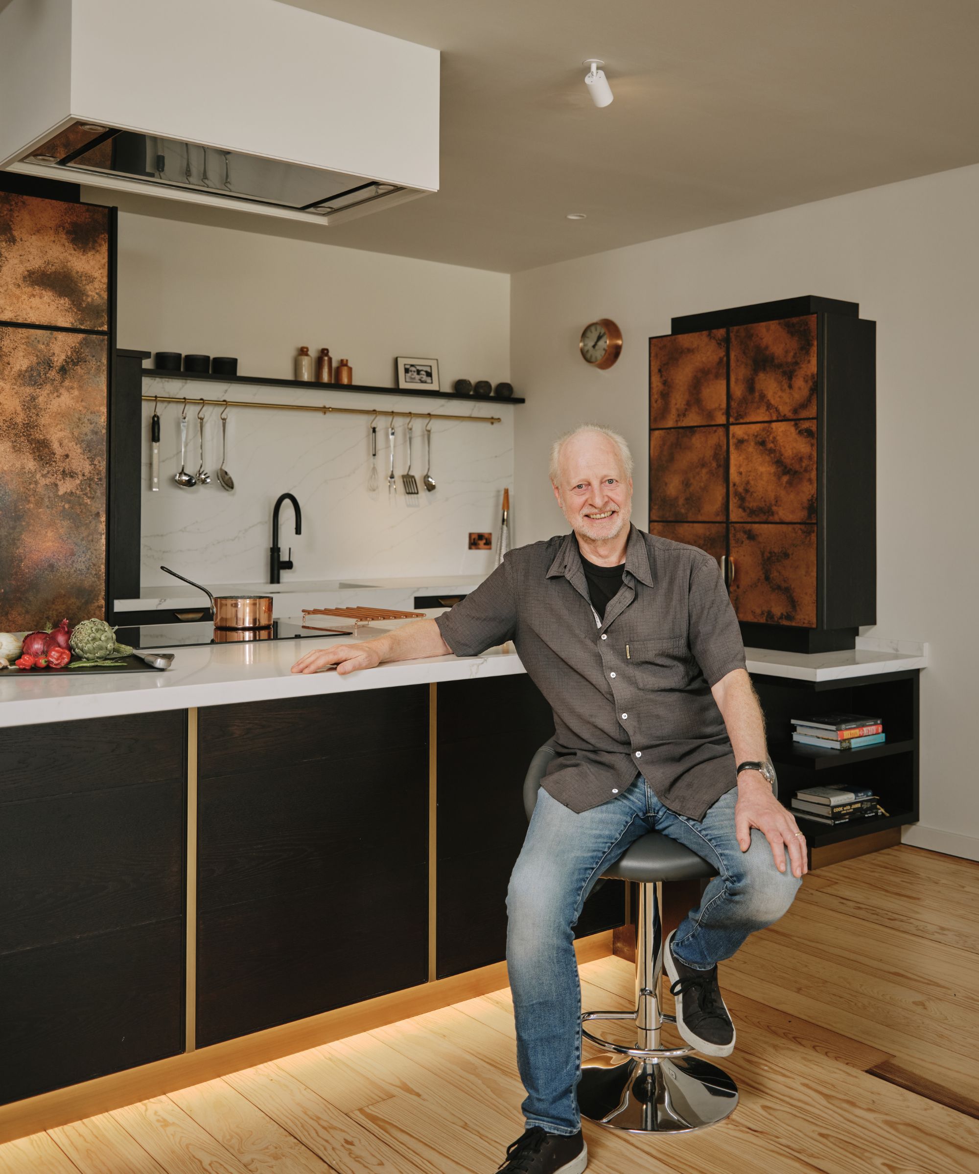 Charlie Smallbone sits on a stool in a modern kitchen