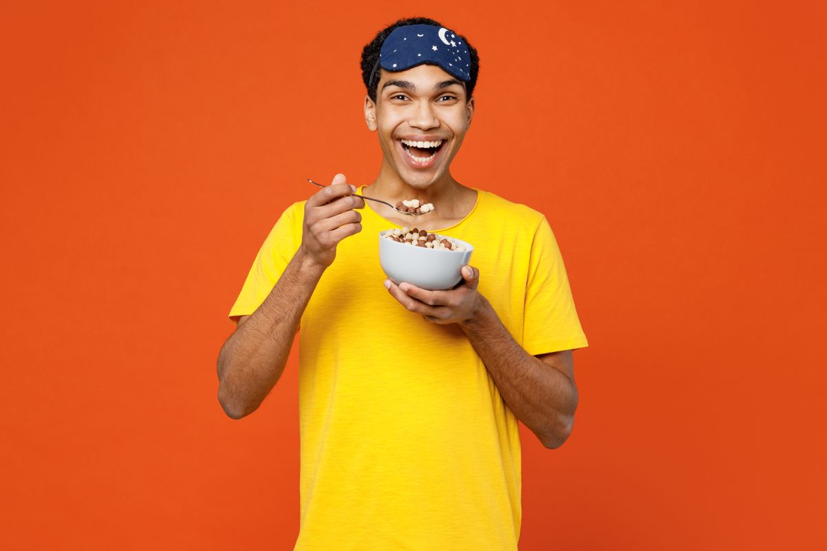 A person eating cereal against a color background