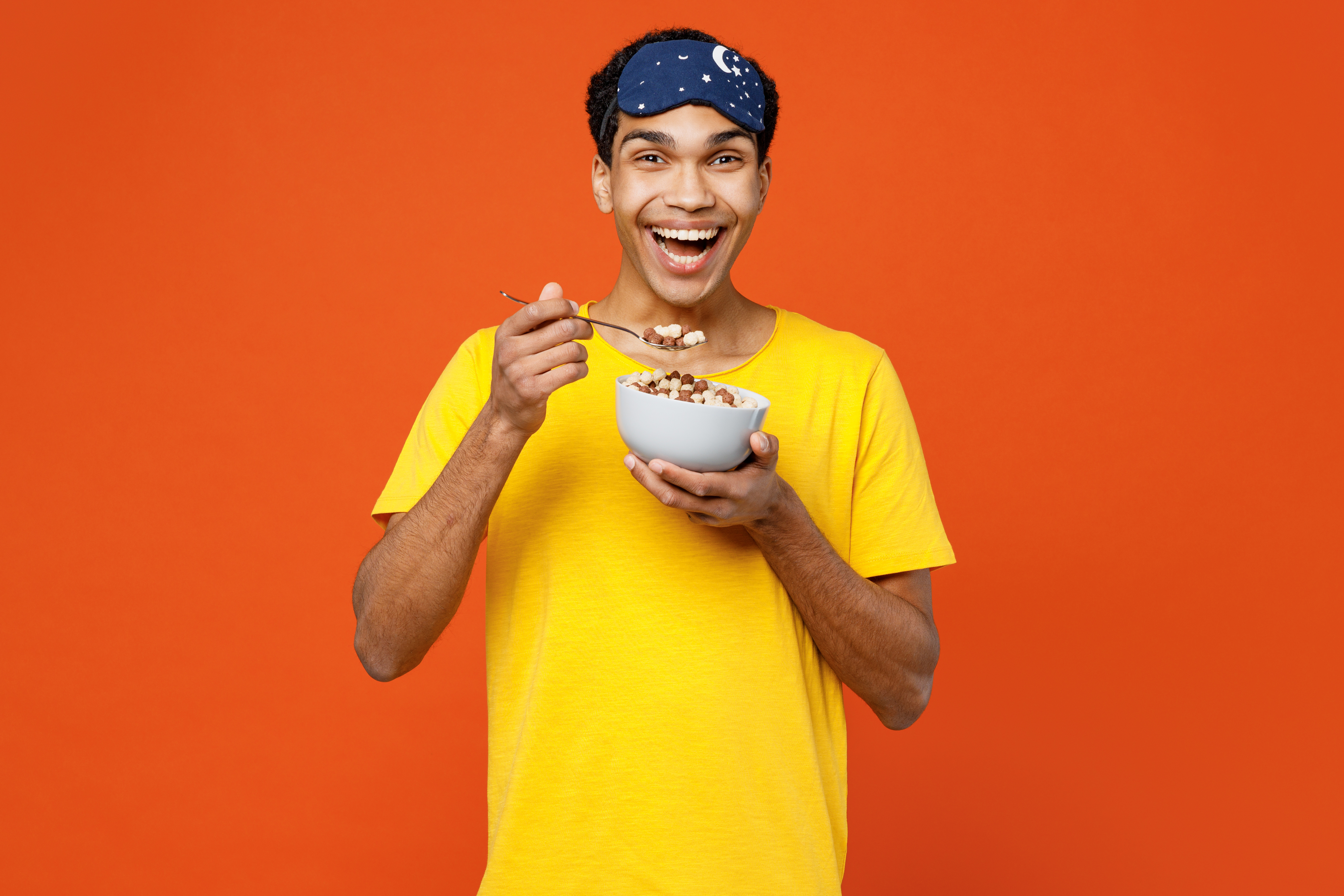 A person eating cereal against a color background