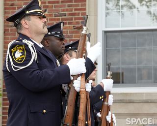 Police stand in a line with ceremonial guns