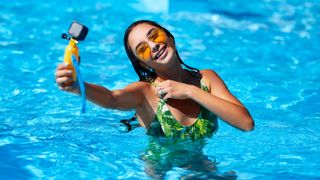 A young woman vlogging in a swimming pool with an action camera