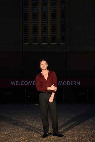 Andrew Scott wearing a red henley shirt with dark trousers at the Gucci Cruise 2025 show.