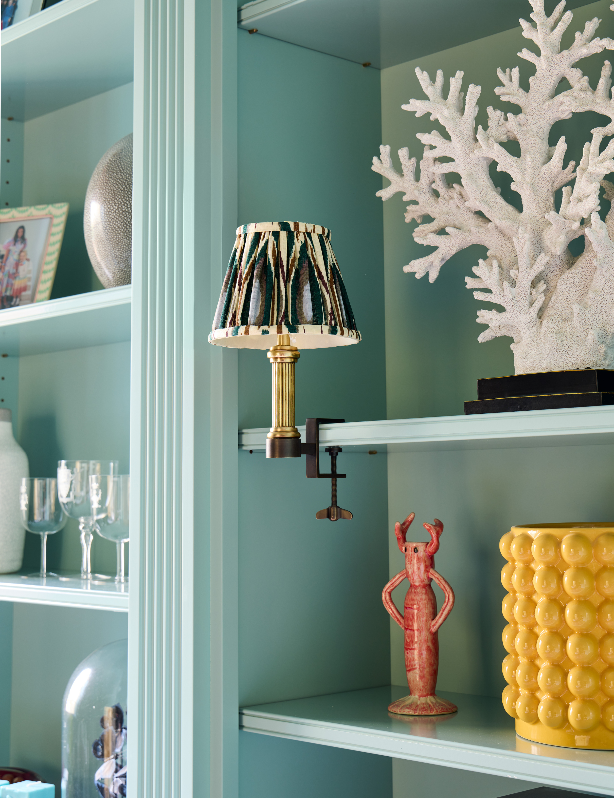 Pooky Bronte Library Light with an ikat shade affixed to a light blue bookshelf with assorted objects