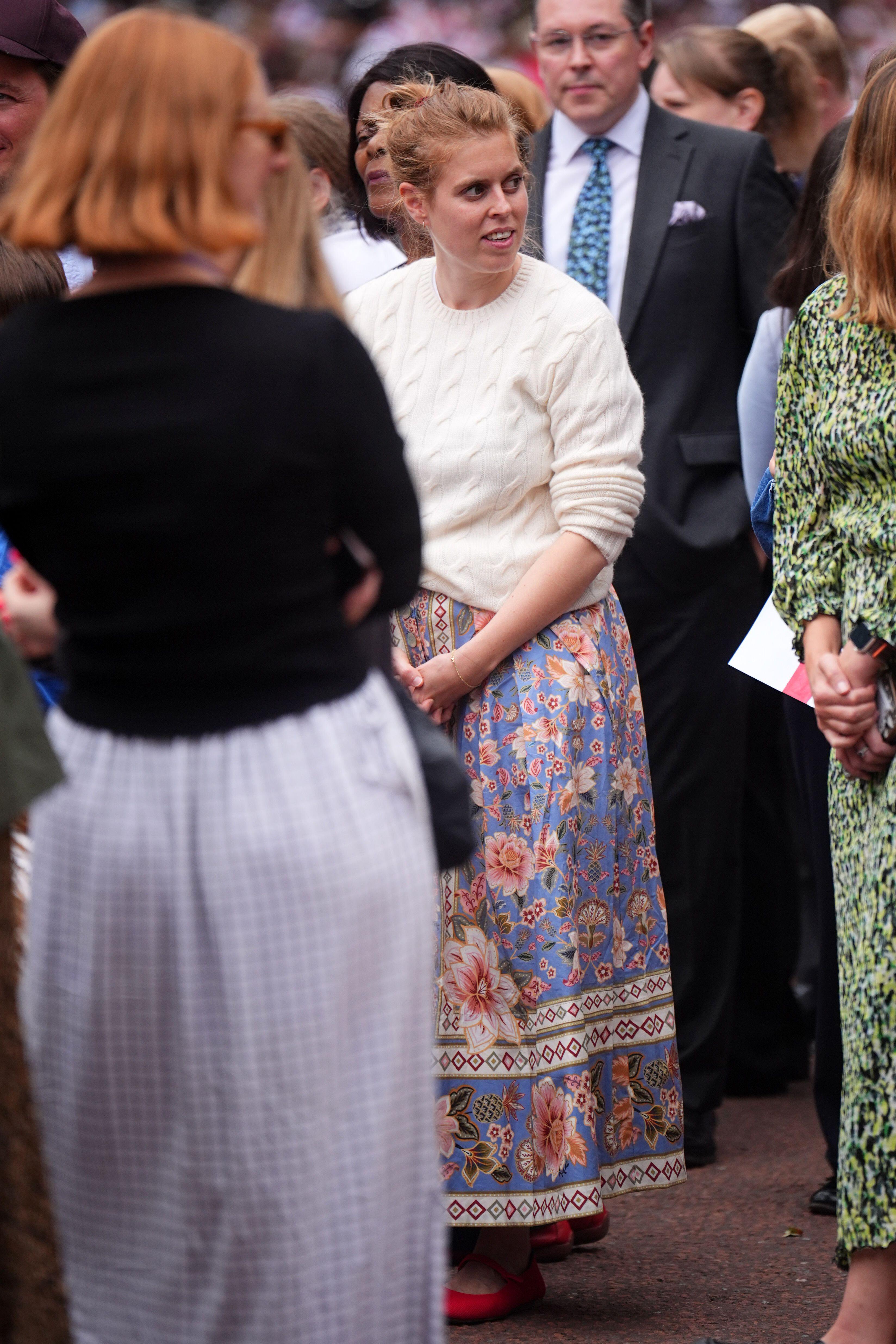 Princess Beatrice wearing a cream sweater and blue floral skirt in a crowd of people