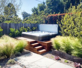 hot tub on a patio surrounded by ornamental grasses and planting