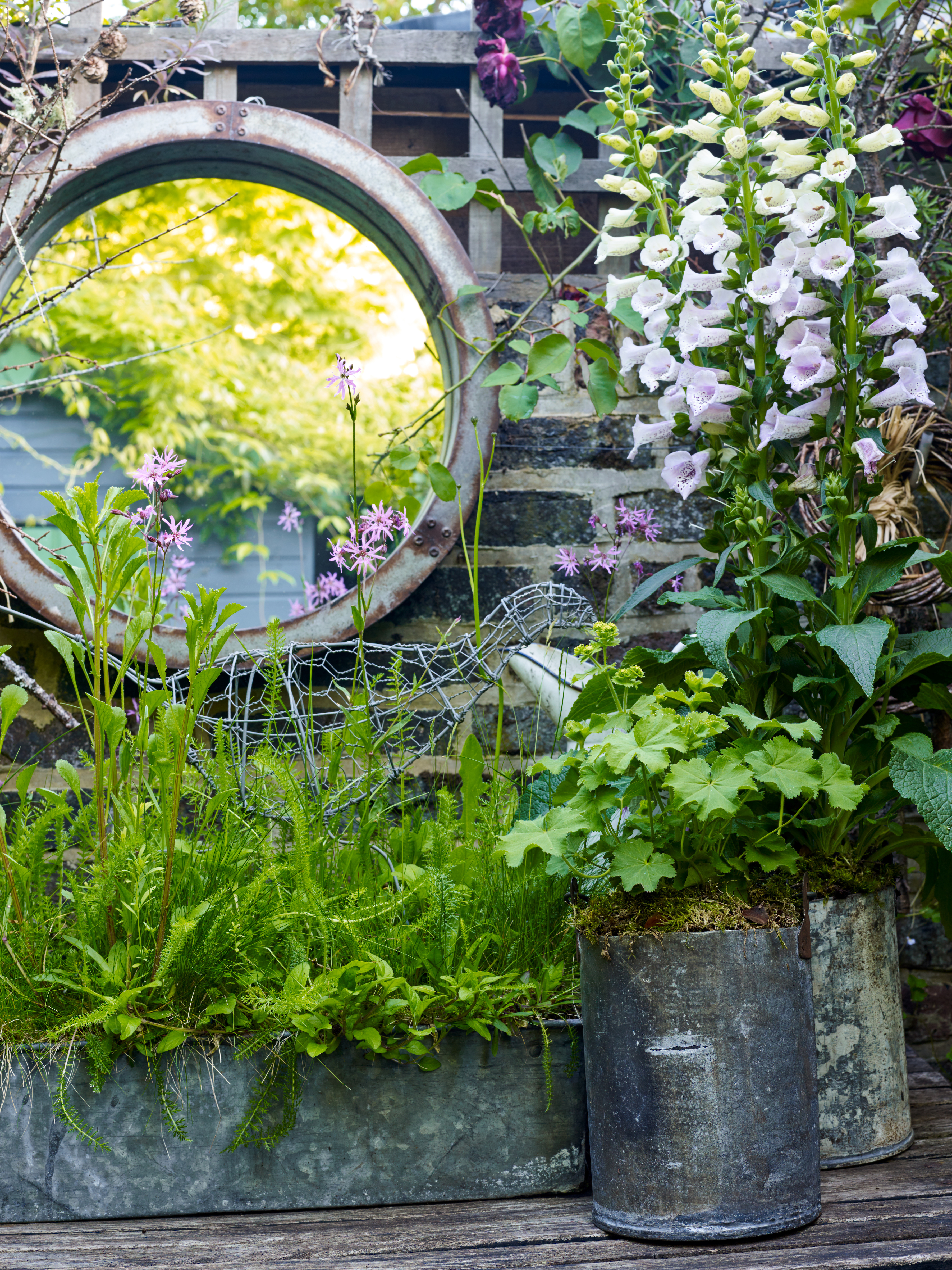 round garden mirror in potting area of small garden