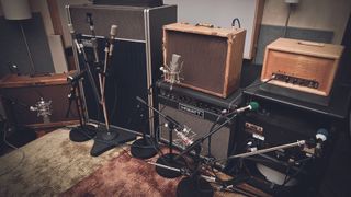 A collection of guitar amplifiers and guitar cabinets in a recording studio