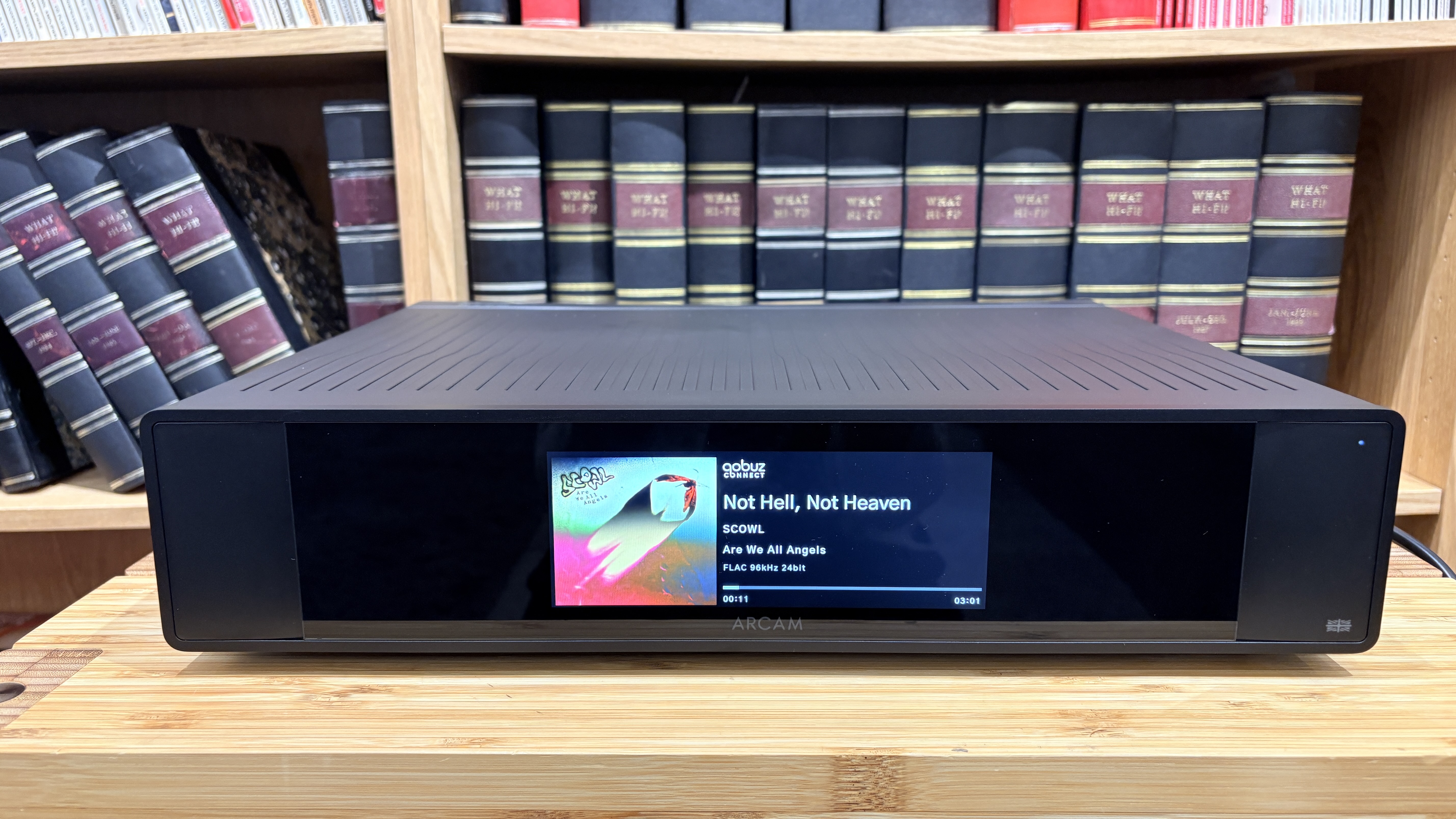 Arcam ST25 music streamer on wooden rack with bookshelf behind it