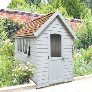 grey shed with cedar roof in cottage style garden