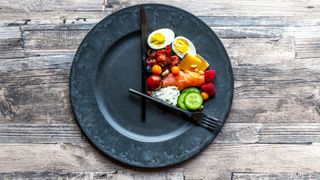 Healthy foods sitting on a plate with knife and fork arranged like a clock
