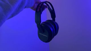 Turtle Beach Stealth 500 gaming headset being held by a reviewer against a wall with blue lighting