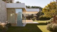 A spacious outdoor garden with trees, bushes, and white furniture