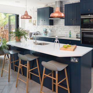 kitchen with blue cabinets white countertop table with white seat wooden flooring