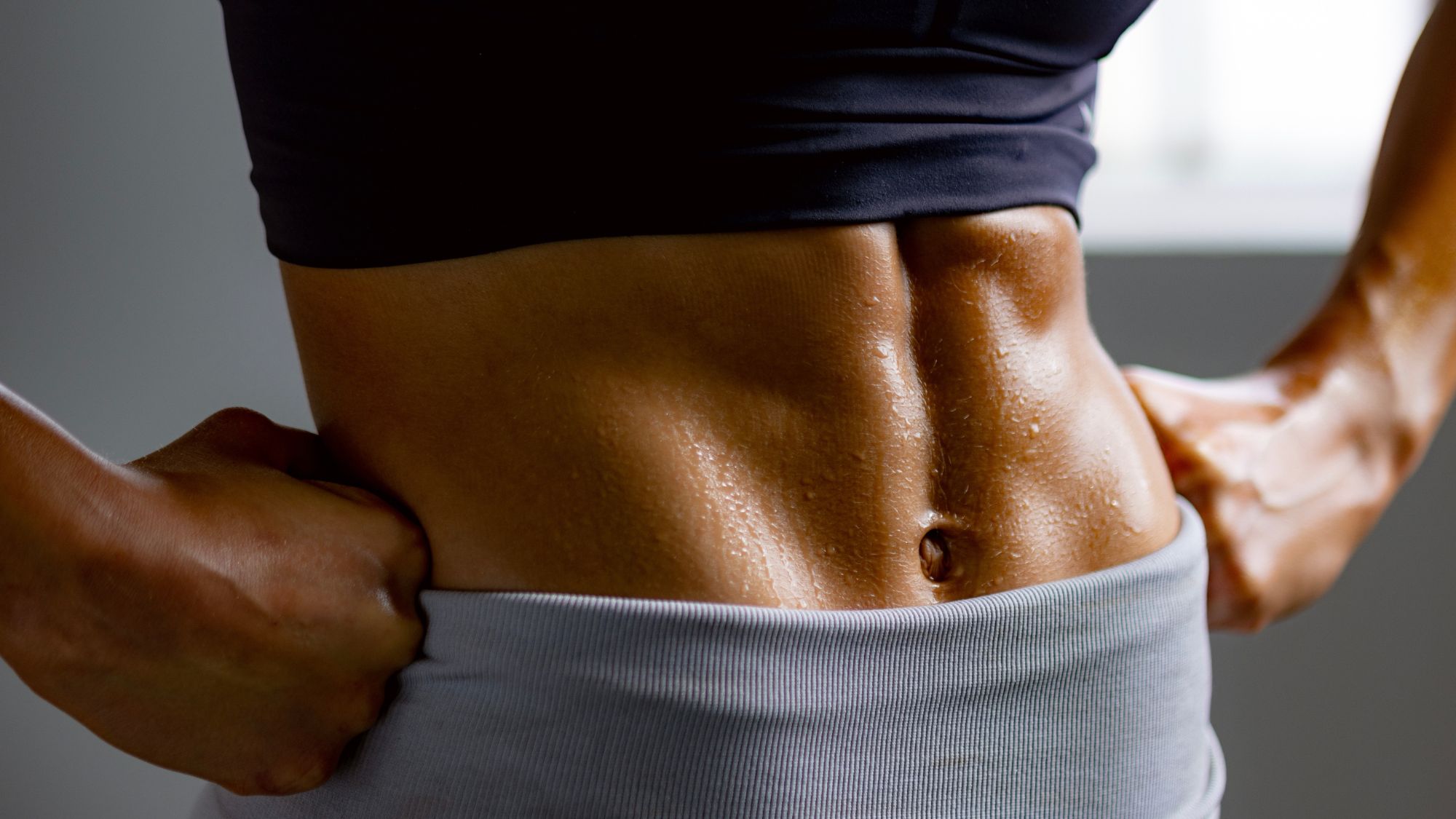 Woman in workout clothes, close up of muscled stomach after trying an In and Out ab method workout