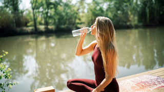 Woman drinking water by lake