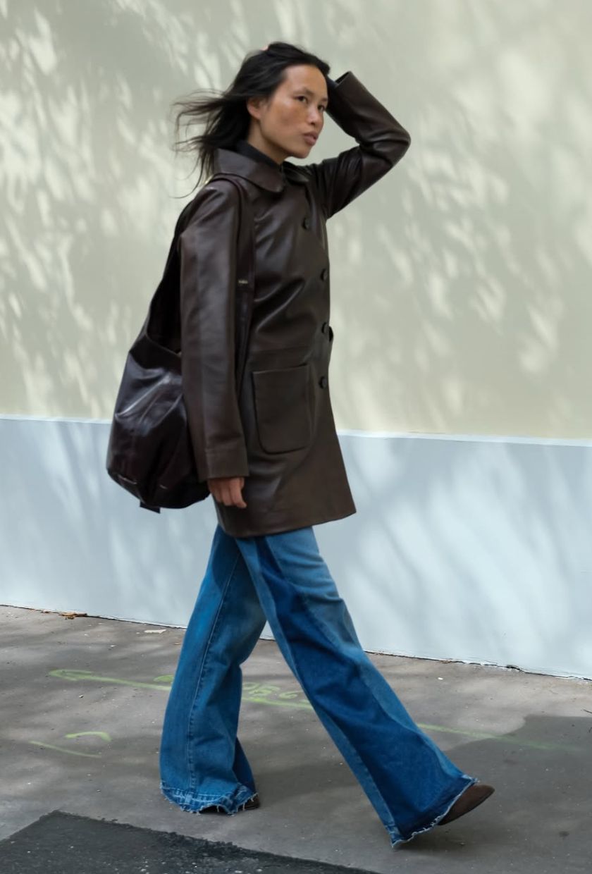 @vikilefevre wears two-tone flare jeans with a brown leather coat, suede boots and a leather tote