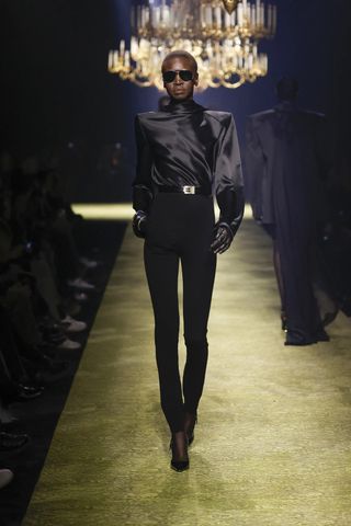 model wears black leggings with a silk blouse in Saint Laurent fall winter 2023