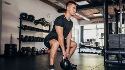 Man doing squat with kettlebell