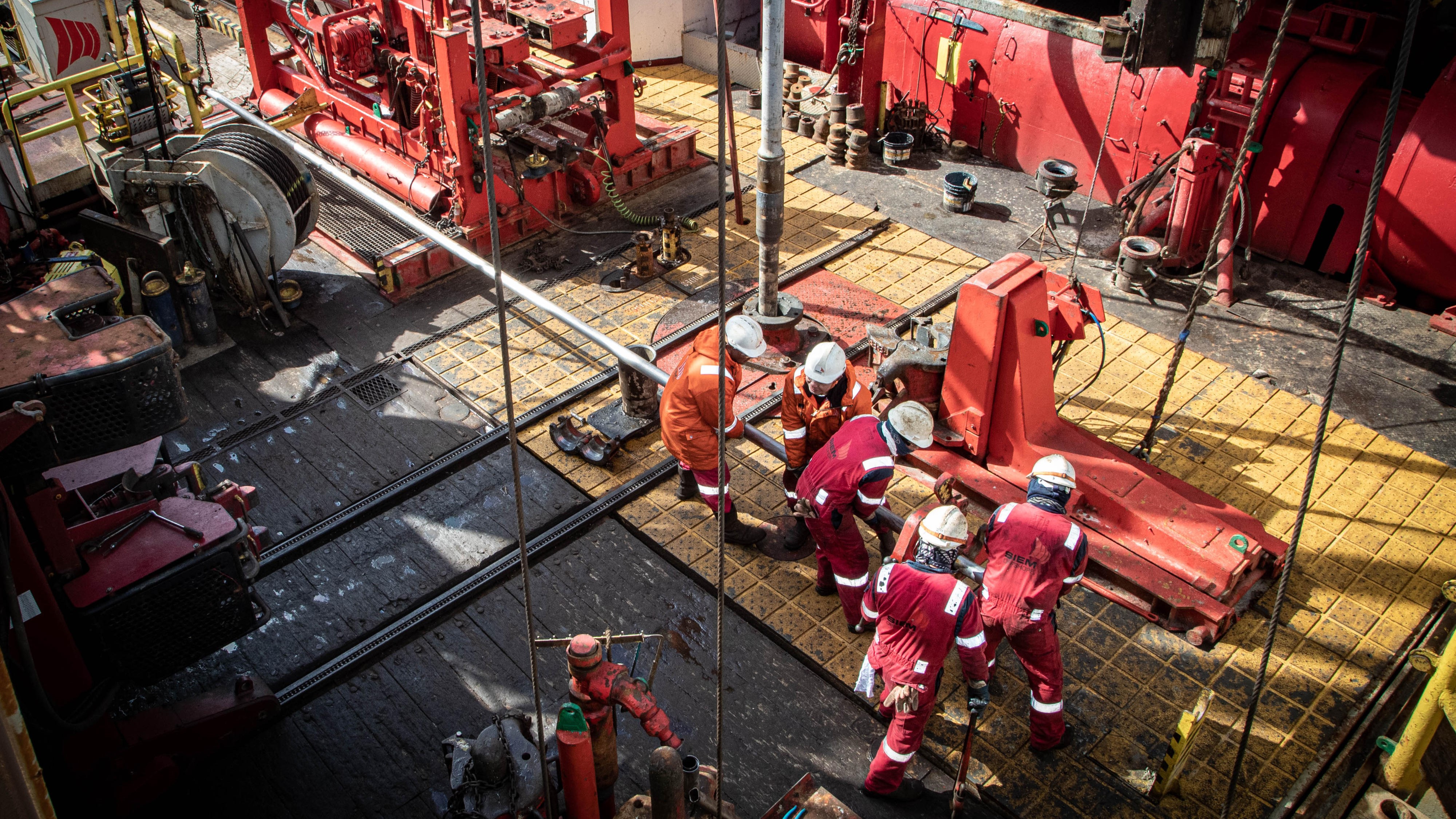 Vessel personnel lay down a core barrel on the rig floor to extrude the recovered core.