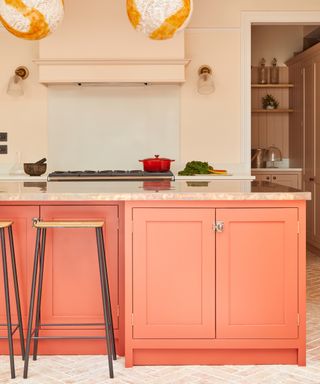 Shaker kitchen with coral island, pink walls, bar stool, tiled floor, marble top