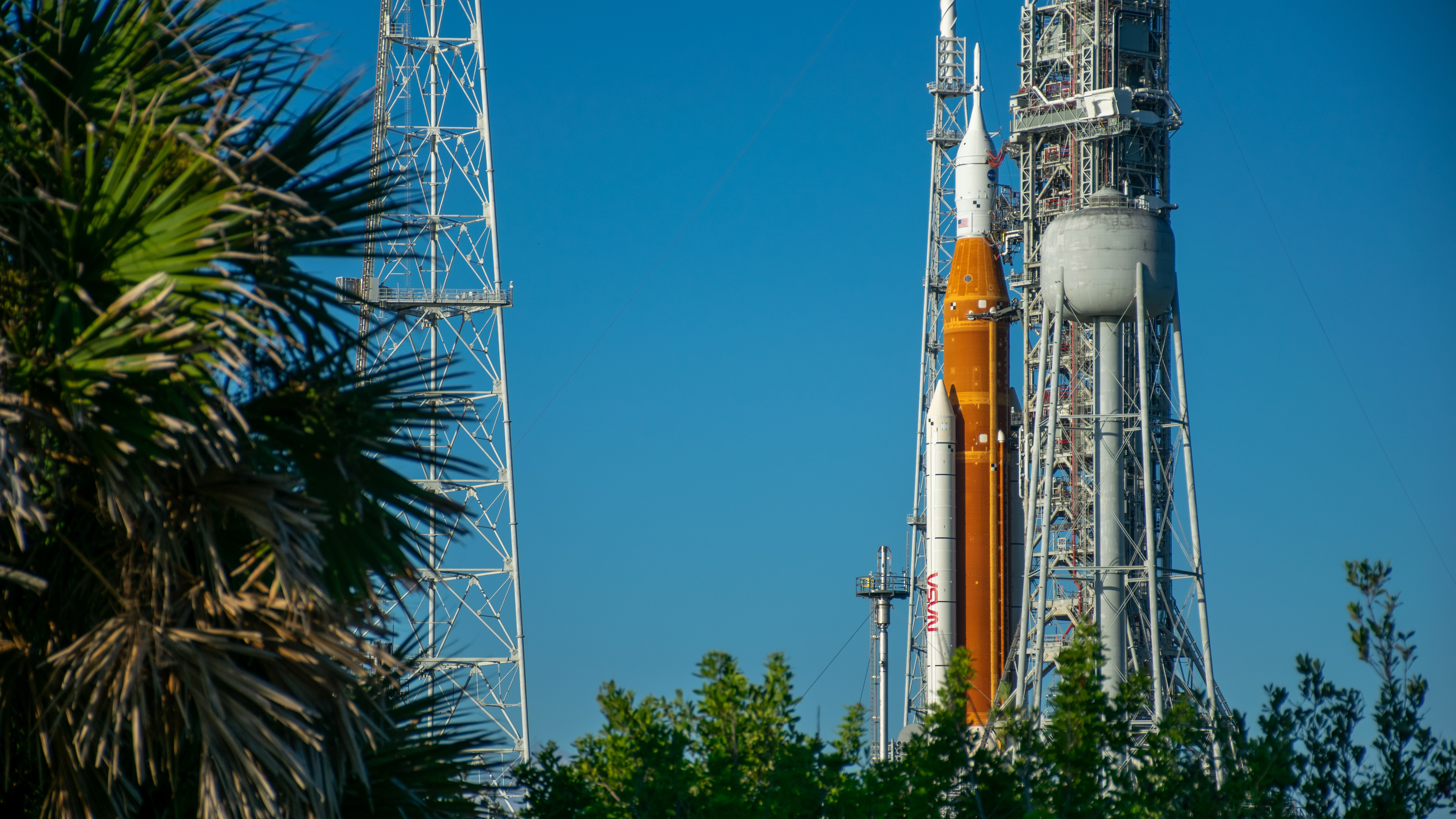 An orange rocket with a white top stands against a dynamic sky.