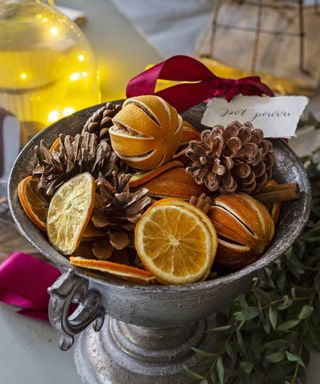 Footed bowl with orange slices and pine cones