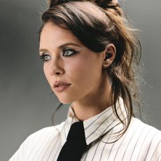 Cropped image of actress Mia Tomlinson wearing a white pinstripe shirt with a black tie. 