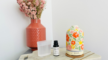 An essential oil diffuser with a water jug and bottle of essential oil.