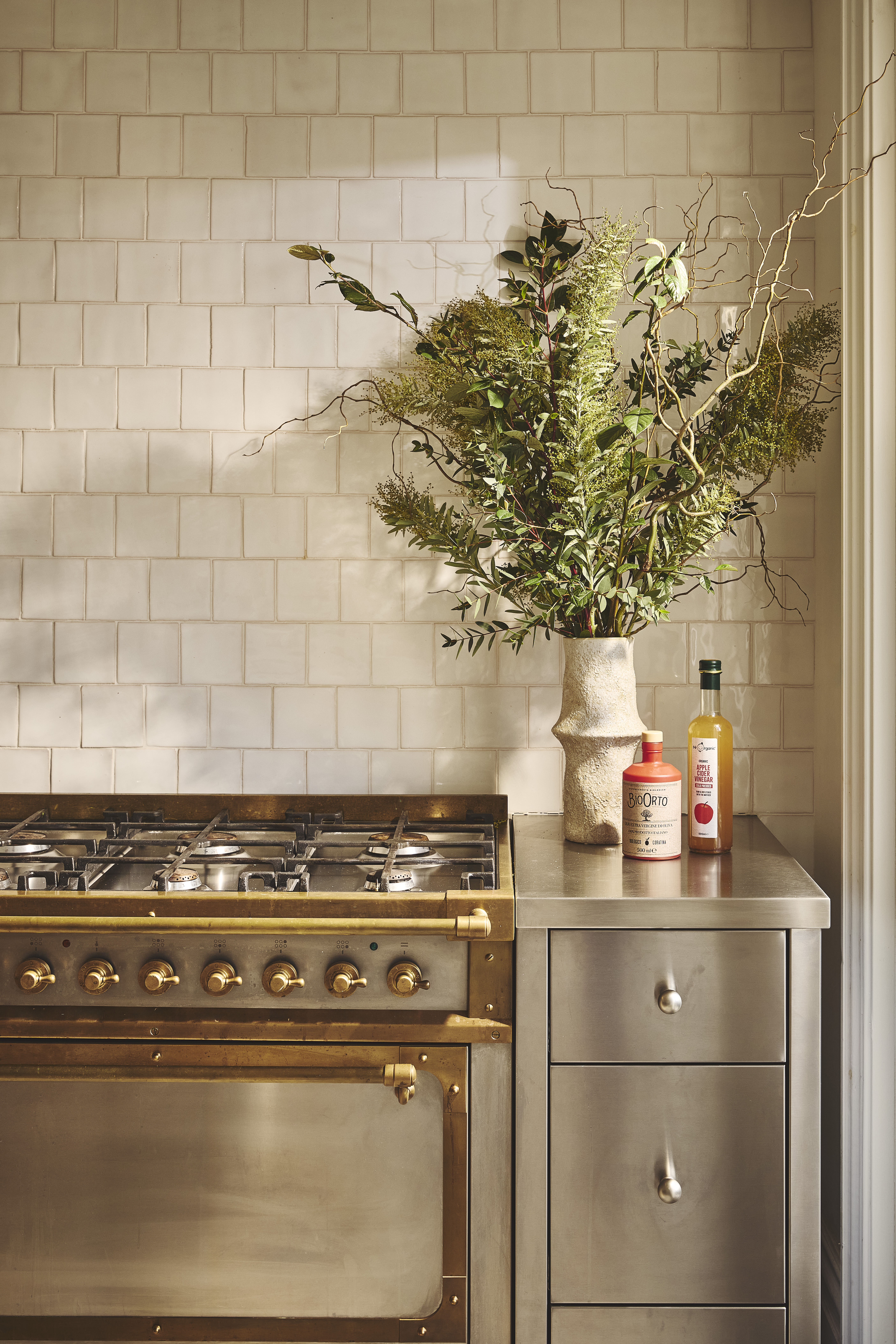 white tiled backsplash in a modern kitchen with stainless steel cabinetry and a mixed metal range cooker