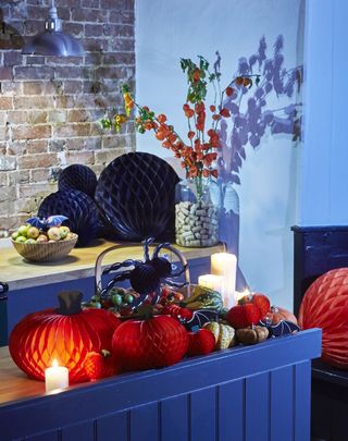A Halloween tablescape decorated with real and paper pumpkins and candles