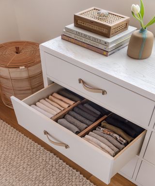 white drawer unit showing open drawer with three rows of clothing separated by drawer dividers, file fold method displayed on tops