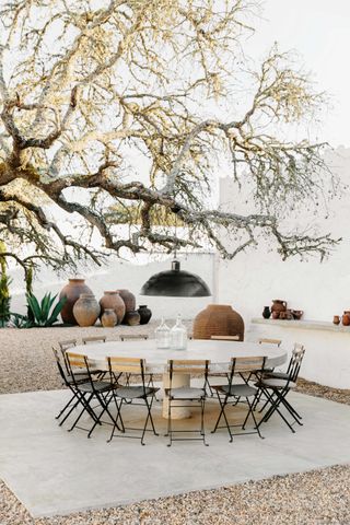 a backyard with a dining table under a large tree