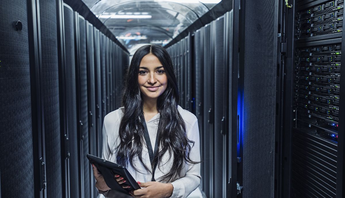 Mixed race technician holding digital tablet in server room - stock photo