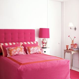 bedroom with white wall and pink bed with pillows