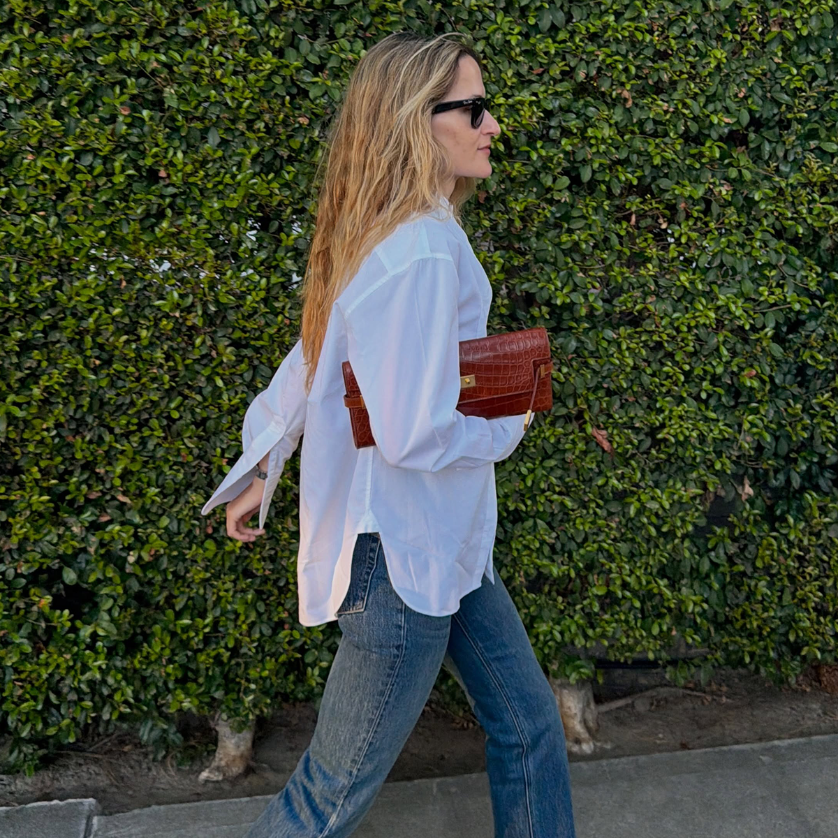 Eliza Huber wearing a white tuxedo shirt, Aflalo Bronte jeans, and Bottega Veneta sandals.