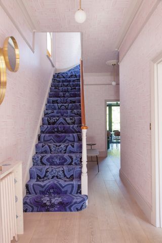 Pink hallway with wallpapered walls and ceilings and blue wallpapered stairs