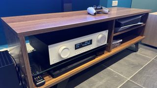 A white JBL MA310 AV amplifier pictured nestled on a shelf in a rack