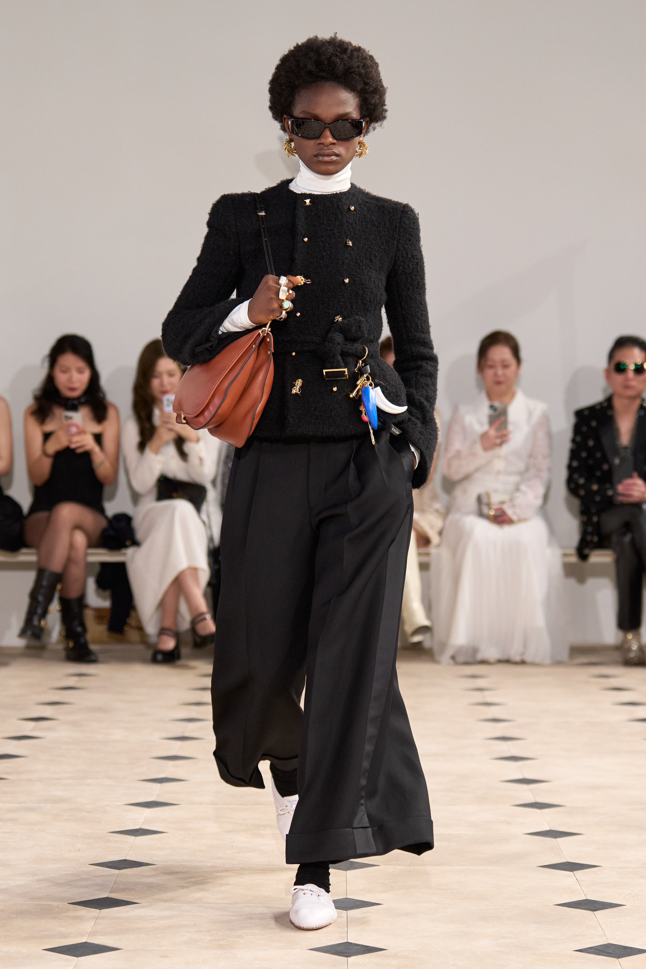 a model walks the Celine runway wearing a bouclé jacket and wide leg pants