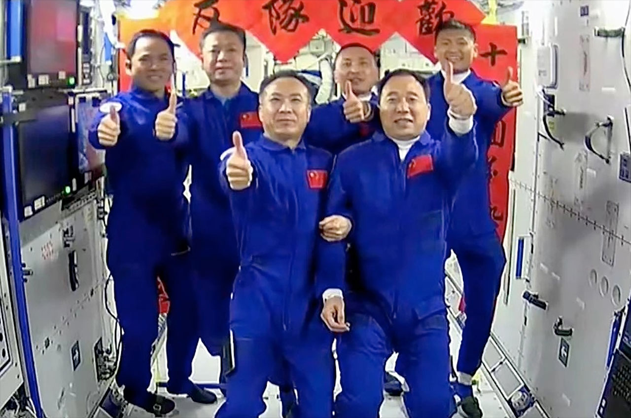 Six Chinese astronauts in blue jumpsuits inside space station