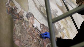 a restorer works on the Alexander the Great mosaic