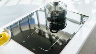a built-in black induction hob with a pot on top of it
