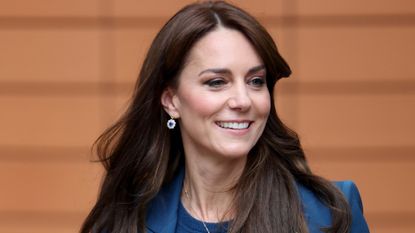 Kate Middleton wearing a blue jacket and sweater smiling