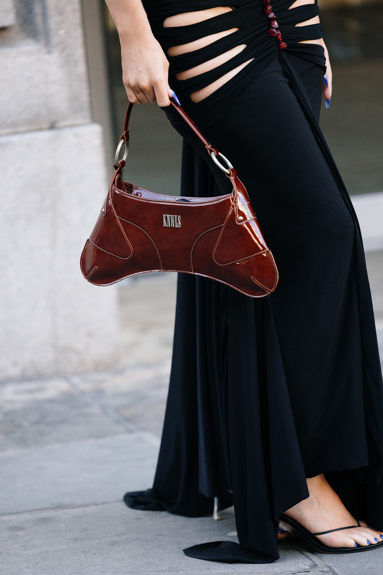 a close up of a woman's black skirt, red bag, and blue nails