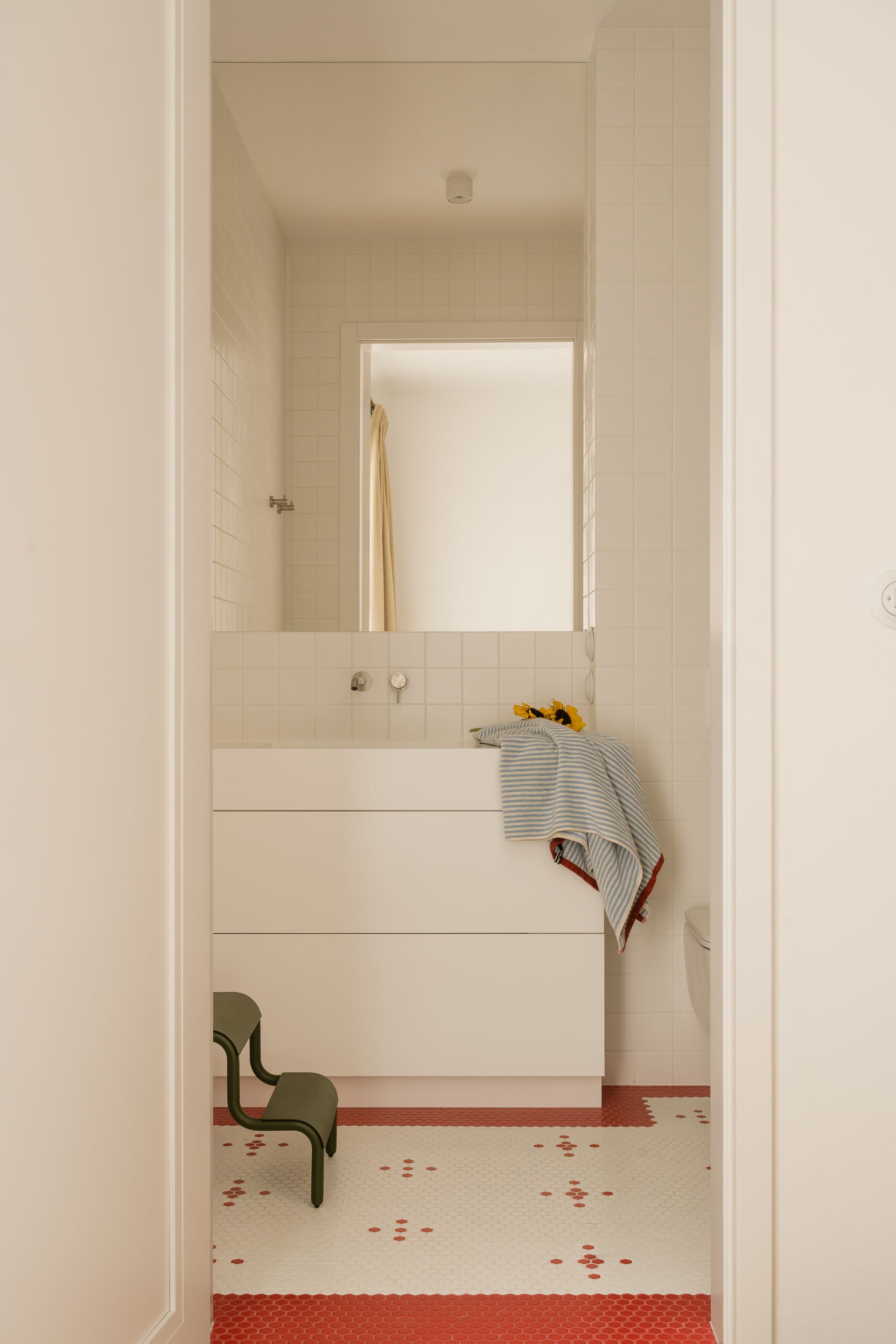 A white bathroom accented with red tiles