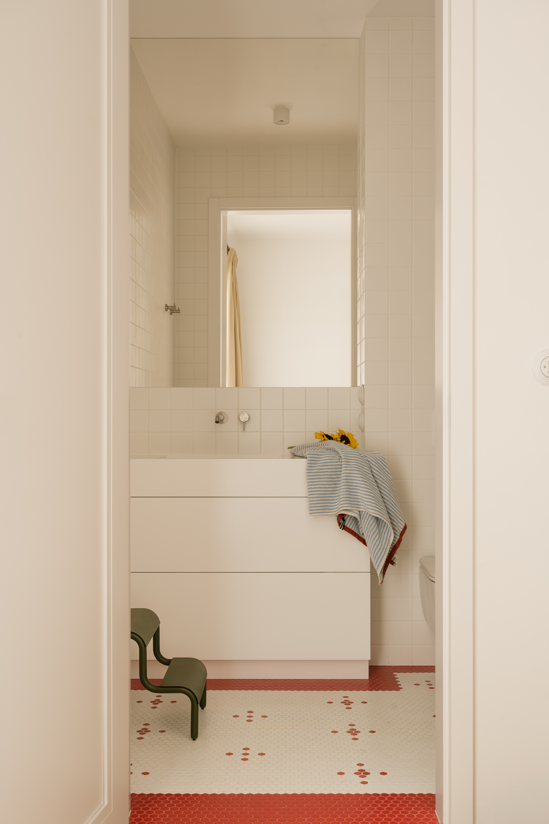 A white bathroom accented with red tiles