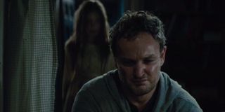 Pet Sematary Jason Clarke looking concerned in the basement, with his zombie daughter behind him