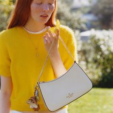 Woman in yellow top carrying kate spade white bag